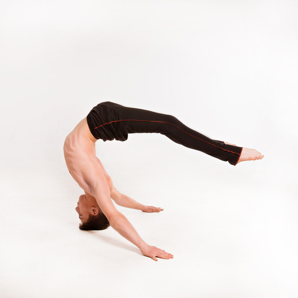 slender man doing gymnastic exercises. Gymnast standing on hands - Fotoğraf, Görsel