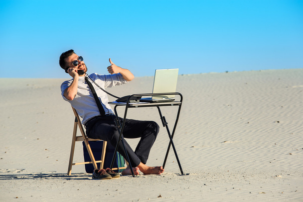 Businessman using  laptop in a desert - Photo, Image