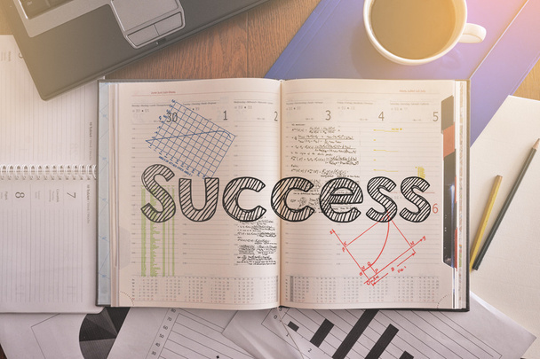 Notebook with text inside Success on table with coffee, laptop and some diagrams - 写真・画像