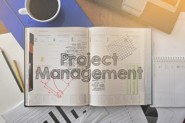 Cuaderno con texto dentro de Project Management en la mesa con café y algunos diagramas
 - Foto, Imagen