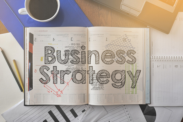 Блокнот з текстом всередині бізнес-стратегії на столі з кавою і деякими діаграмами
 - Фото, зображення