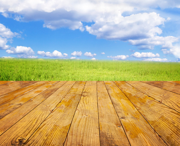 Campo verde sotto il cielo blu. Pavimento in legno
 - Foto, immagini