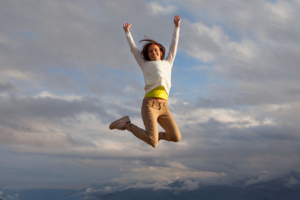 young beautifull girl oa a peak of a mountait jumping - Valokuva, kuva