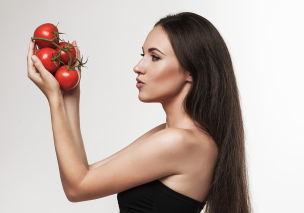 Portret van jonge fit vrouw met glanzende rode tomaten - Foto, afbeelding