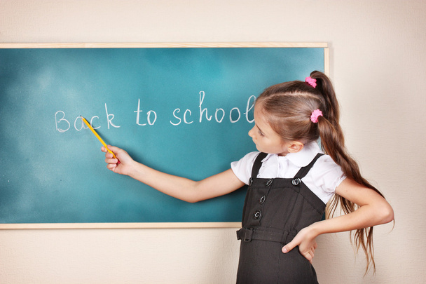 Beautiful little girl standing near blackboard in the classroom - Foto, immagini