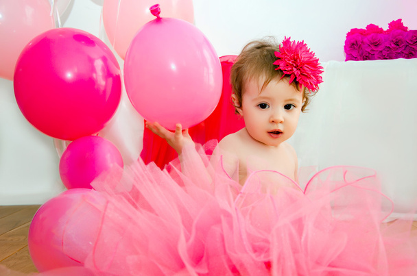 Vauva pörröisessä vaaleanpunaisessa hameessa, ilmapalloilla ja isoilla numeroilla 1
 - Valokuva, kuva