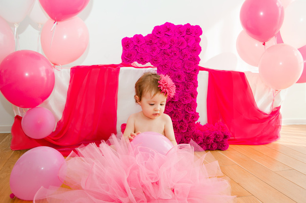 first birthday.Baby in fluffy pink skirt, with balloons and a big Digits 1 - Foto, immagini
