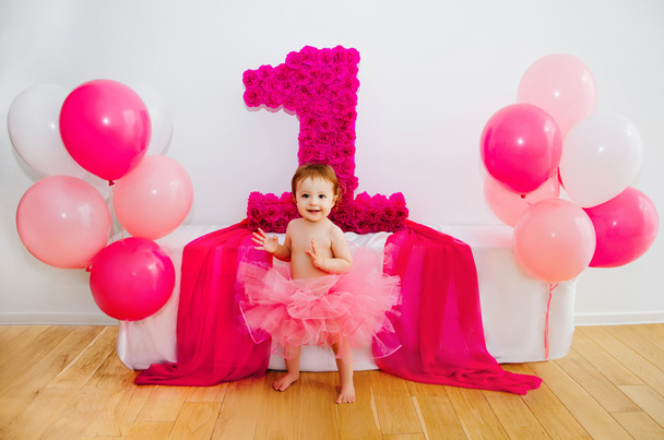 first birthday.Baby in fluffy pink skirt, with balloons and a big Digits 1 - Фото, изображение
