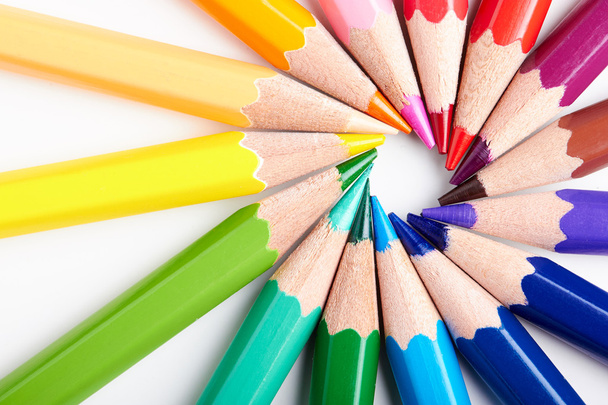Conjunto de lápices multicolores acostados sobre mesa blanca orden redondo
 - Foto, imagen