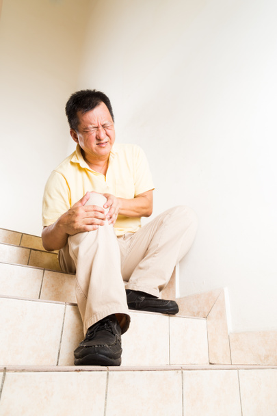 Homme mûr souffrant de douleurs articulaires aiguës au genou assis sur les escaliers
 - Photo, image