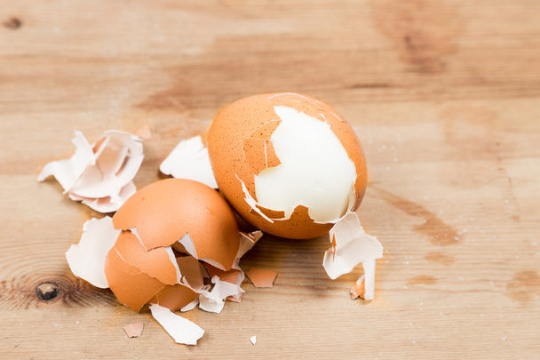 Hard boiled organic eggs with shell peeled on wooden table - Photo, image