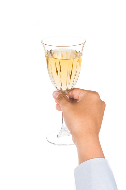 Χέρι που κρατά το κρύσταλλο οίνου γυαλί με λευκό κρασί, ενώ έτοιμο σε τοστ και ζητωκραυγές - Φωτογραφία, εικόνα
