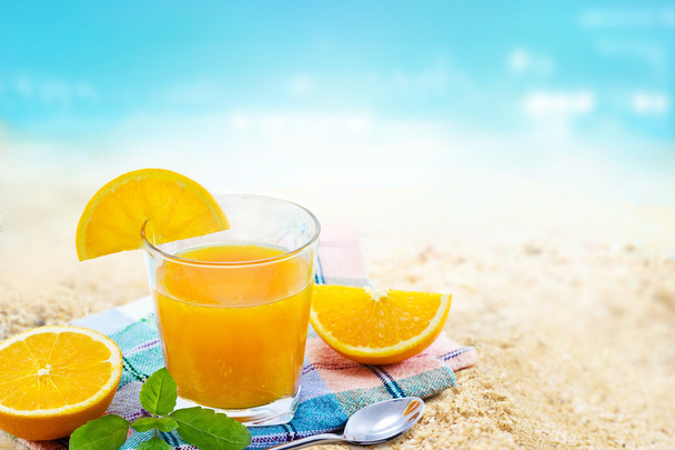 Świeży sok pomarańczowy z mięty na tkaninie w szkło na morze piasek plaża letni dzień - Zdjęcie, obraz