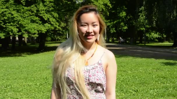 young attractive happy asian woman turns over and smiles in the park - smiles to camera - Footage, Video