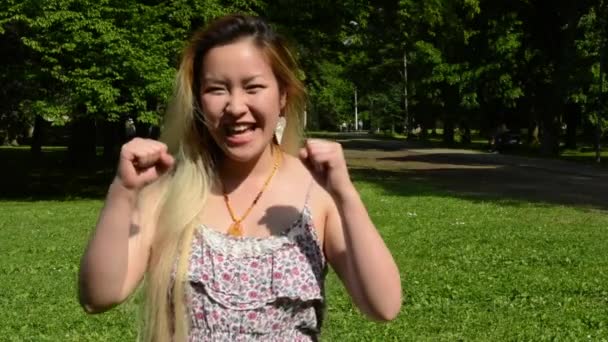 молодая привлекательная счастливая азиатка переворачивается и улыбается в парке - улыбается в камеру
 - Кадры, видео