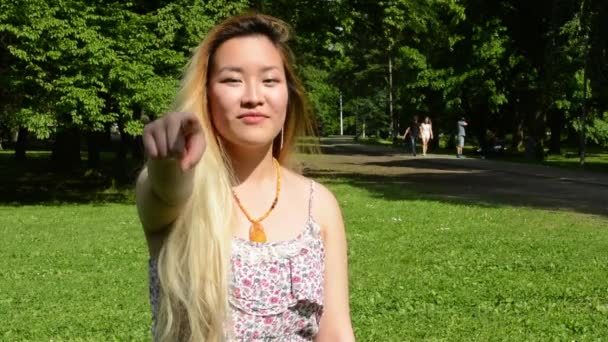 jovem atraente asiático mulher mostra dedo para a frente no parque
 - Filmagem, Vídeo