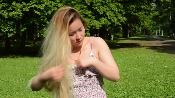 νεαρή ελκυστική Ασιάτισσα προσαρμόζει τα ρούχα και τα μαλλιά της στο πάρκο - στυλ - κοντά - Πλάνα, βίντεο