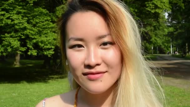 młoda azjatycka atrakcyjna szczęśliwa kobieta w parku - uśmiecha się do kamery - detal - Materiał filmowy, wideo