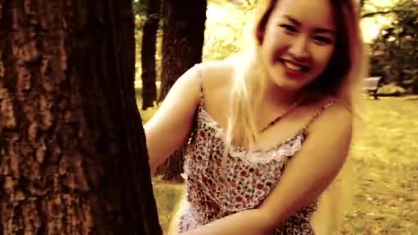 young attractive happy asian woman turns over and smiles in the park - smiles to camera - Séquence, vidéo