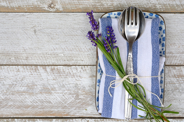 ασημένια μαχαιροπίρουνα και μια μπλε λευκό πετσετάκι πετσέτα κουζίνας με λεβάντα διακόσμηση και αντίγραφο άδειο χώρο σε στιλ ρουστίκ vintage χώρα - Φωτογραφία, εικόνα