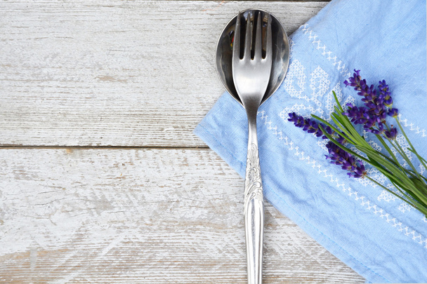 silbernes Besteck und ein blau-weißes Serviettenhandtuch mit Lavendeldekoration und leeren Kopierraum im rustikalen Vintage-Landhausstil - Foto, Bild
