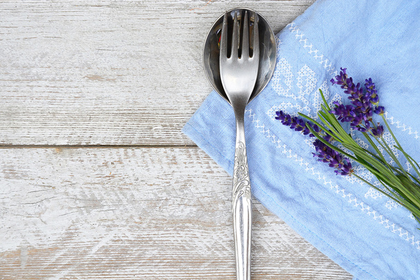 zilveren bestek en een blauw wit servet keuken handdoek met lavendel decoratie en lege kopie ruimte in rustieke vintage landelijke stijl - Foto, afbeelding