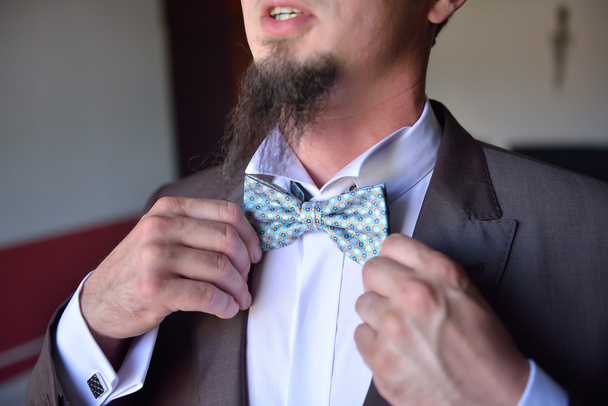 Mid section of happy groom adjusting his bow tie - Zdjęcie, obraz