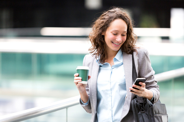 Young attractive business woman using smartphone drinking coffee - Photo, image
