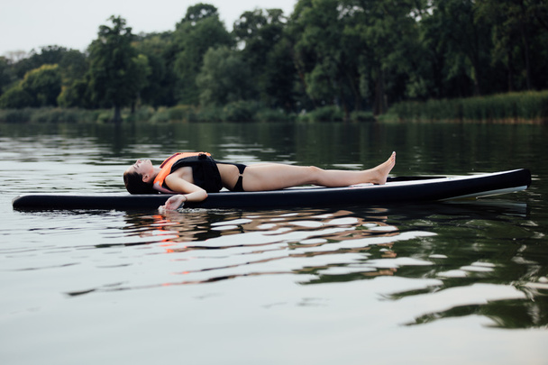 woman lying on a paddle board on water - Foto, Imagem