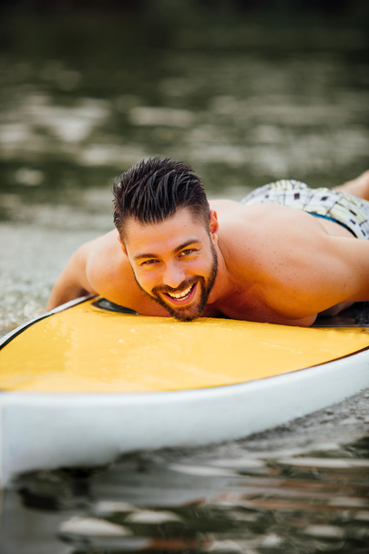 athletic man swimming on a paddleboard - Photo, Image
