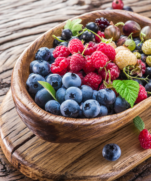 Ripe berries in the wooden bowl. - Zdjęcie, obraz