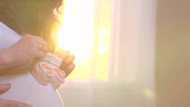 Pregnant  woman holding baby shoes - Séquence, vidéo