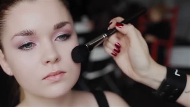 Professional make-up applying blush on cheekbones. Close-up. Front view. Pan shot. - Footage, Video