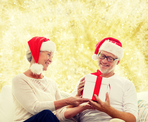 happy senior couple in santa hats with gift box - Fotó, kép