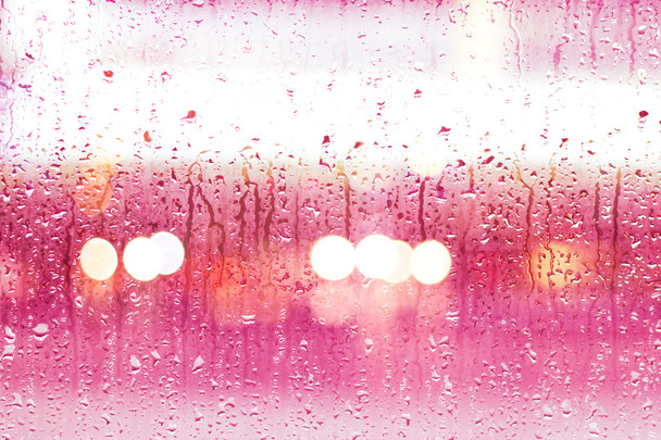 Streszczenie krople deszczu na tle kolorowe szkło, lampy uliczne, nieostrość - Zdjęcie, obraz