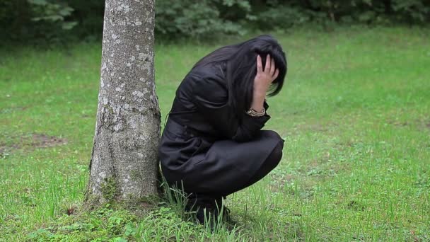 Depressed woman sitting near the tree in the park - Footage, Video