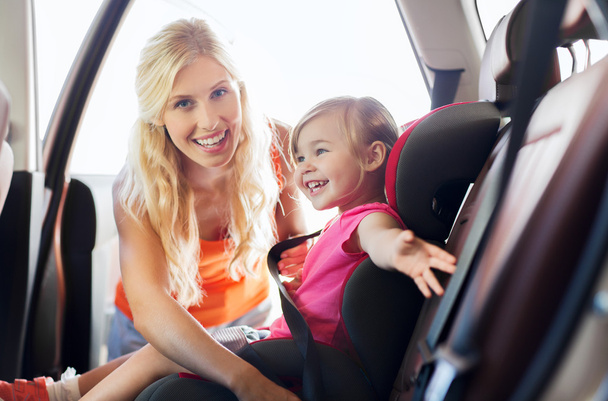 счастливая мать пристегивает ребенка ремнем безопасности автомобиля
 - Фото, изображение
