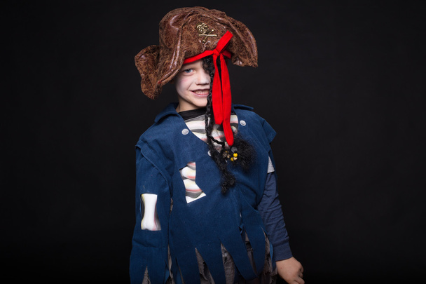 Adorable young boy dressed in a pirate outfit, playing trick or treat for Halloween. Studio portrait over black background - Foto, Imagem