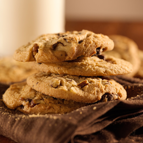 Chocolate chip cookies and glass of milk in background - Photo, Image