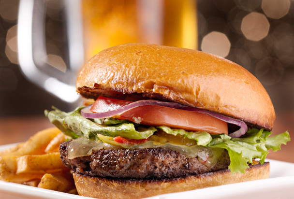 Gourmet-Cheeseburger mit Bierkrug im Hintergrund - Foto, Bild