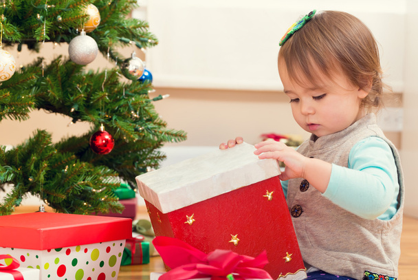 girl opening presents under her Christmas tree - Foto, immagini