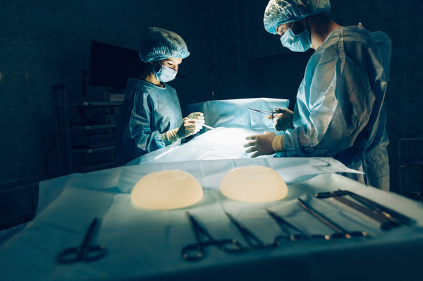 Team di chirurghi che lavorano con il monitoraggio del paziente in sala operatoria chirurgica. aumento del seno
. - Foto, immagini