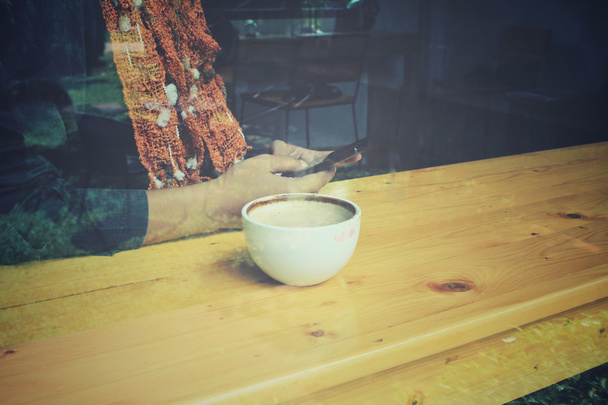 Nainen juo kahvia älypuhelimella istuu sisällä trendikkäässä urbaanissa kahvilassa
. - Valokuva, kuva