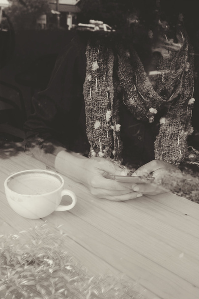 Nainen juo kahvia älypuhelimella istuu sisällä trendikkäässä urbaanissa kahvilassa
. - Valokuva, kuva