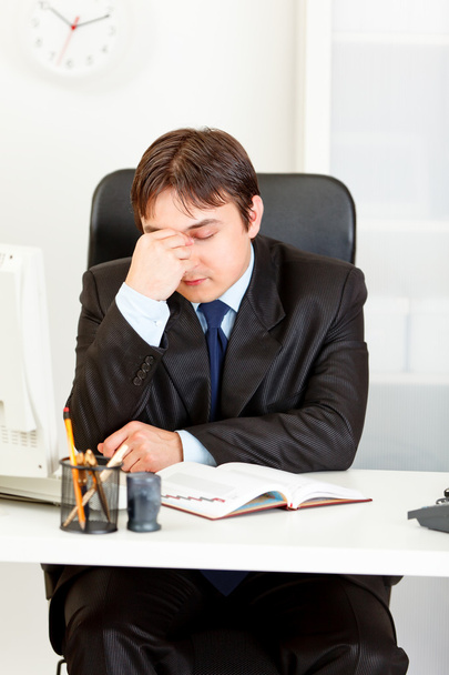 Tired modern businessman sitting at office desk - Photo, image