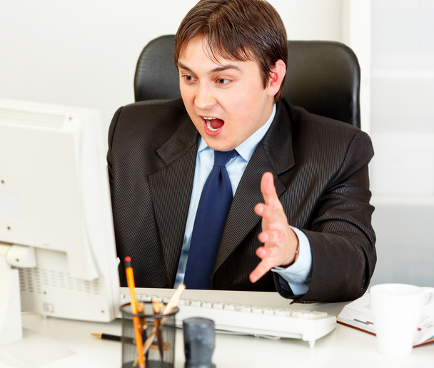 Shocked businessman sitting at office desk and looking at computer monitor - Photo, Image