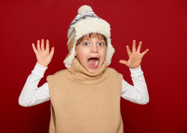 зимняя концепция - девушка в шляпе и свитере с распростертыми объятиями на красном
 - Фото, изображение