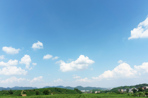 Kylä kirkas, sininen taivas ja valkoiset pilvet
 - Valokuva, kuva