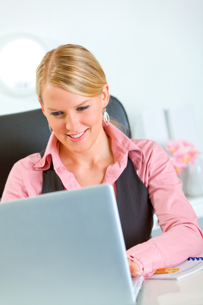 Donna d'affari sorridente che lavora a computer portatile a ufficio
 - Foto, immagini