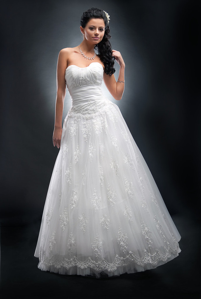 Fashionable young female brunette in white bridal dress posing - Fotó, kép